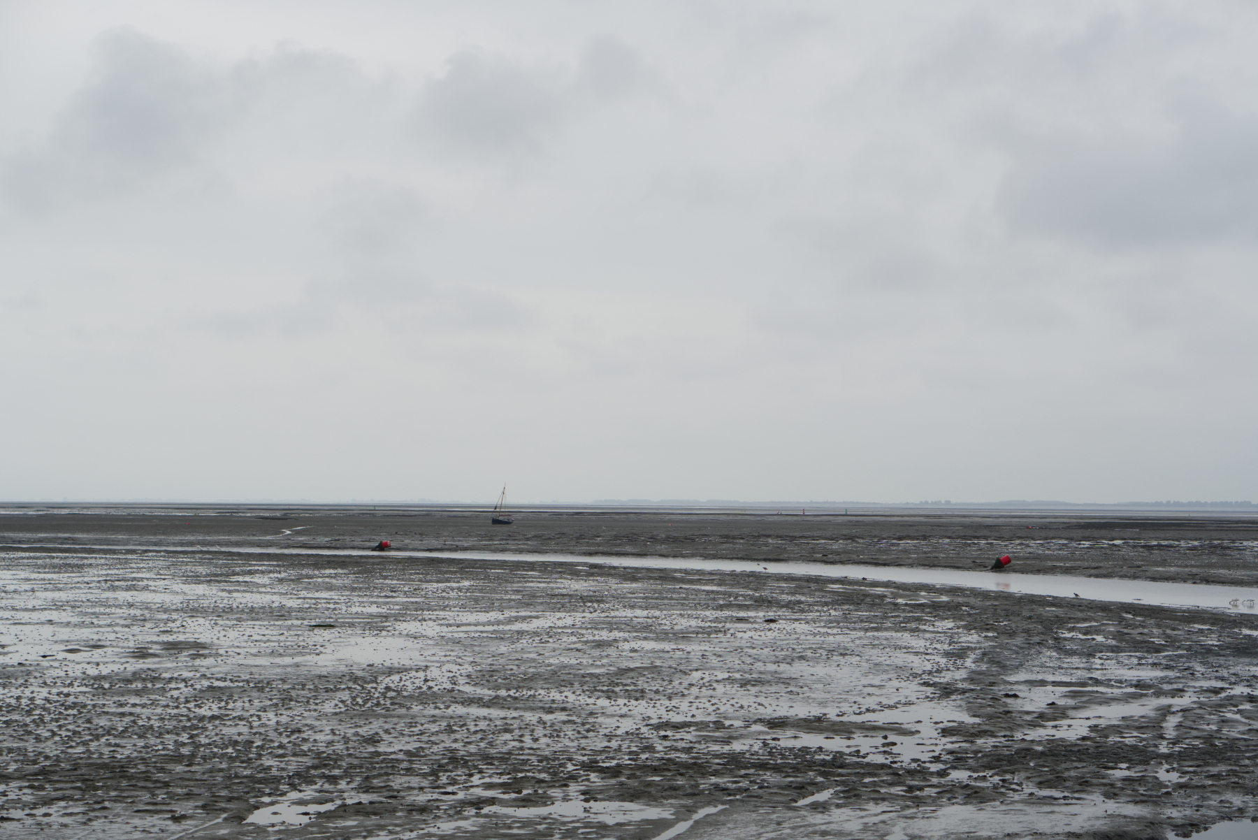 Laag water met een klein bootje op het droogvallend wad langs de vaargeul